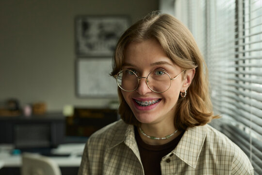 Smiling employee with eyewear looking at camera in corporate office
