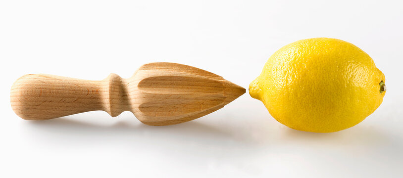 Wooden citrus reamer and whole lemon on white background
