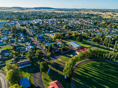 Green trees around Glen Innes Showground ring in bright sunlight from aerial view in summer