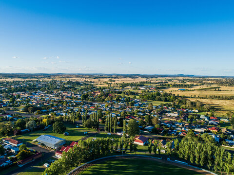 Green trees around Glen Innes Showground ring in bright sunlight from aerial view in summer