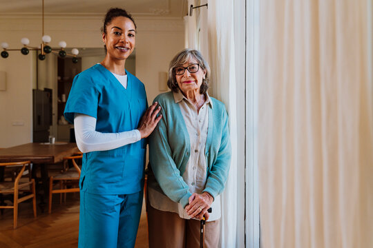 Caregiver supporting senior with walker at home in rehabilitation setting
