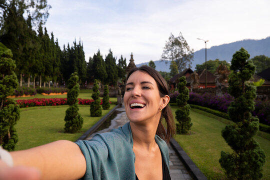 Smiling traveler taking selfie at temple garden in Bali outdoors
