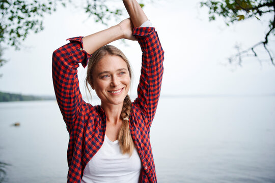 Smiling beautiful woman with arms raised looking away