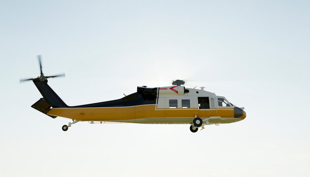 Yellow rescue helicopter flying in the clear sky during the day