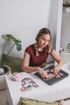Woman scrapbooking memories with instant camera and printed photos indoors