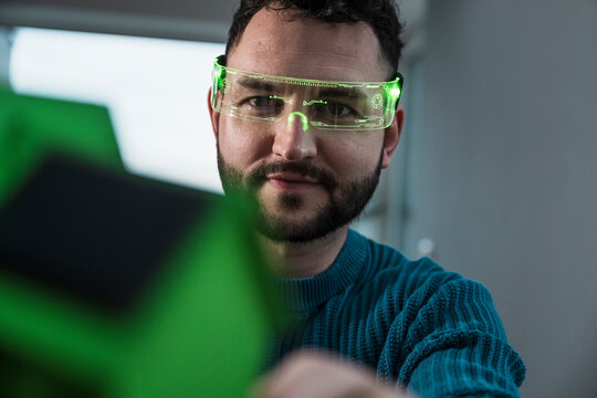 Architect wearing green colored smart glasses and examining model house