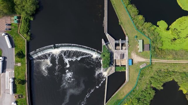 Top down aerial view of Knottingley Weir with cascading water a center fish pass and hydroelectric power station UK