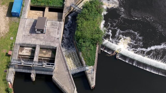 Top down aerial view of Knottingley Weir with cascading water a center fish pass and hydroelectric power station UK