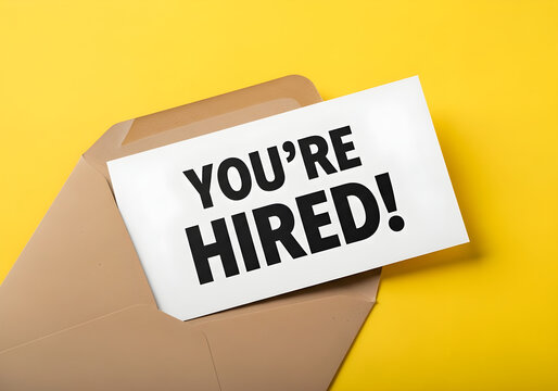 Job offer letter with youre hired text on a white card in a brown envelope on yellow background