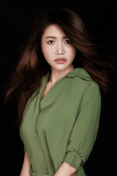 Asian woman in green against a black background