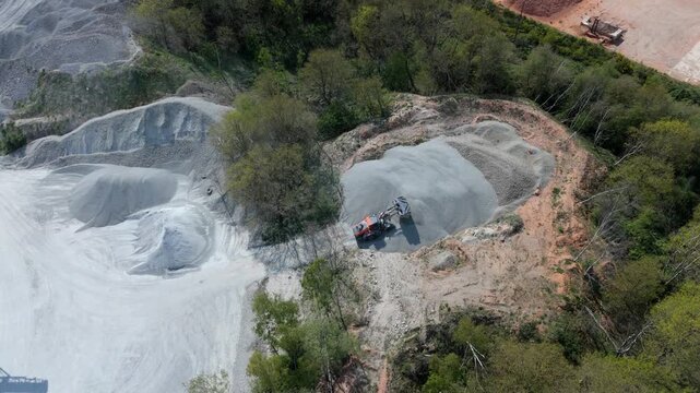 High angle aerial drone view of a heavy plant dumper moving raw materials into a factory hopper in Yorkshire UK