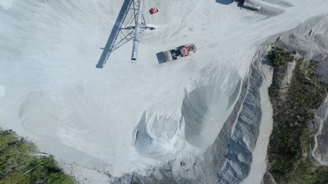Top down aerial view of a heavy plant dumper loading raw material into a hopper in the UK