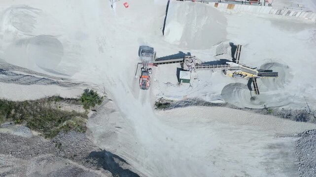 Top down aerial view of a heavy plant dumper loading raw material into a hopper in the UK