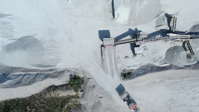 High angle aerial drone view of a heavy plant dumper moving raw materials into a factory hopper in Yorkshire UK