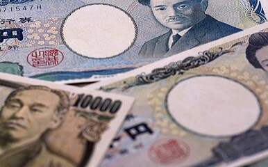 Japanese yen money bills pile on table. Japan banknotes of JPY currency close up. © Larysa
