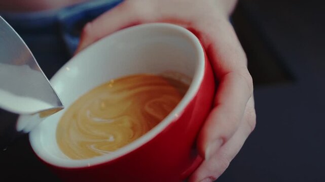 leckerer Cappuccino wird mit Motiv in Tasse gegossen