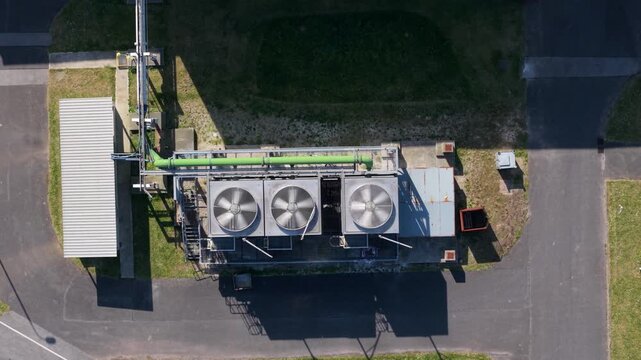Top-down aerial view of industrial turbine cooling fans venting air from a large glass manufacturing plant in Goole, East Yorkshire, UK.