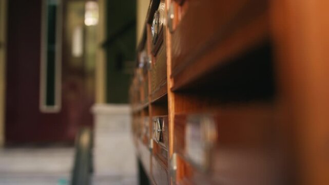 A close-up of a mail carrier placing a letter into a wooden mailbox. The scene captures postal service, communication, and traditional mail delivery. High quality 4k footage