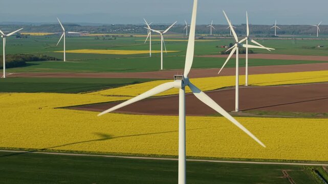 Drone view of sustainable wind generators on a flat patchwork landscape under warm evening golden light near Scunthorpe