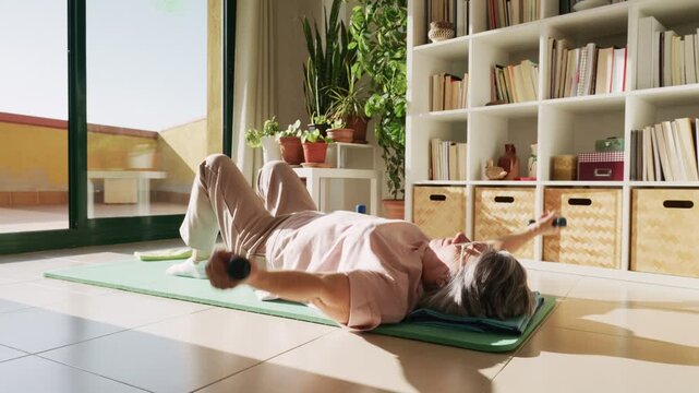 Senior woman training with small dumbbells at home