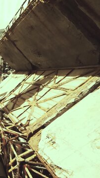 Workers gather near a collapsed roof structure at a construction site in the afternoon. The area shows signs of damage and debris scattered on the ground.
