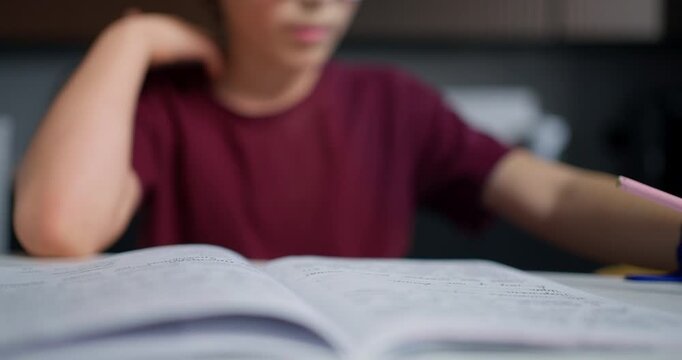 Young Boy With Glasses Takes Short Pause During Homework In Comfortable Kitchen Environment