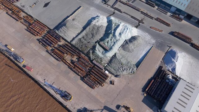 Aerial drone view of raw materials steel beams and iron ore piles stored on a commercial dock near Scunthorpe UK