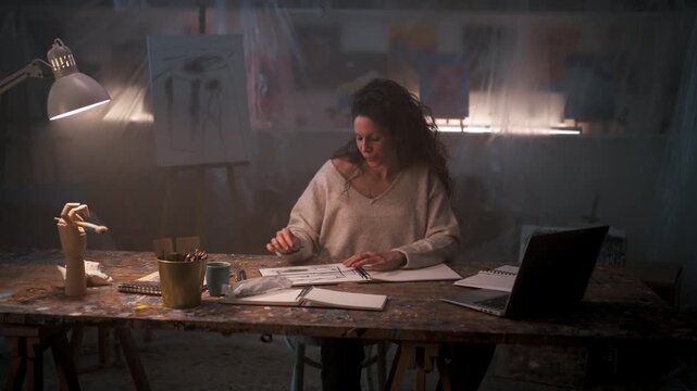 Creative professional sitting at a desk and sketching in a studio warehouse.