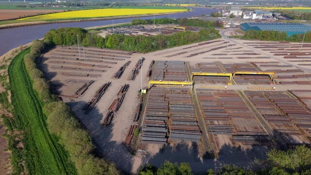 Top down aerial view of steel girders and beams arranged in rows at a river port dock UK