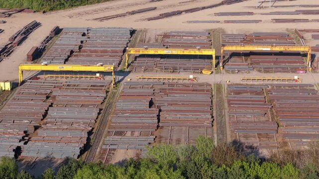 Top down aerial view of steel girders and beams arranged in rows at a river port dock UK