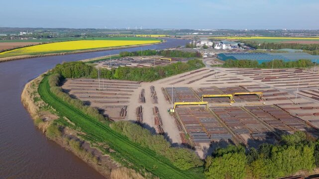 Top down aerial view of steel girders and beams arranged in rows at a river port dock UK