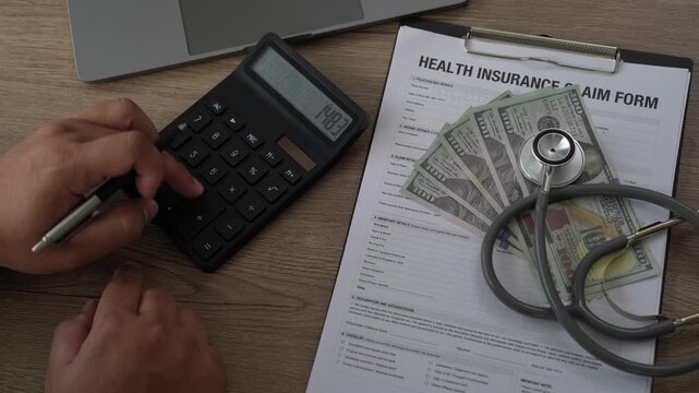 Healthcare cost calculator on health insurance claim form with US dollar bills, stethoscope, and pen on laptop, medical financial planning for hospital expenses and policy coverage budget.