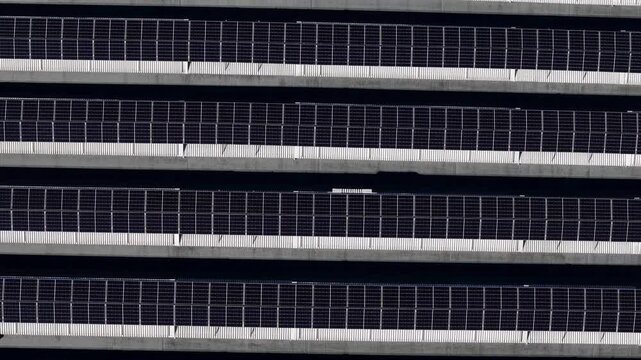 Photovoltaic solar panels on industrial rooftop arranged in parallel rows forming geometric pattern, static top down aerial shot