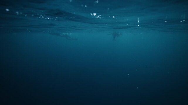 Dark Arctic Ocean underwater with faint light and calm blue water