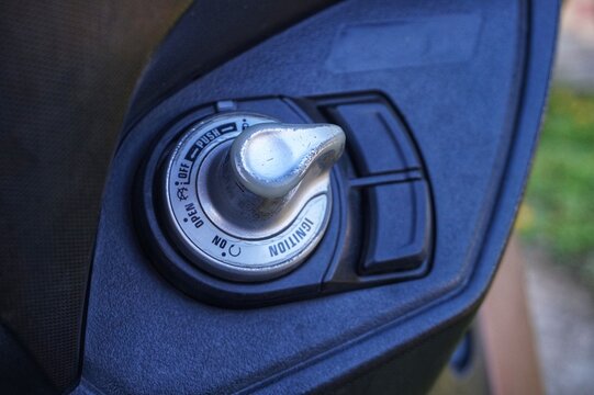 Close-up of a modern motorcycle keyless ignition switch on a dark textured dashboard.
