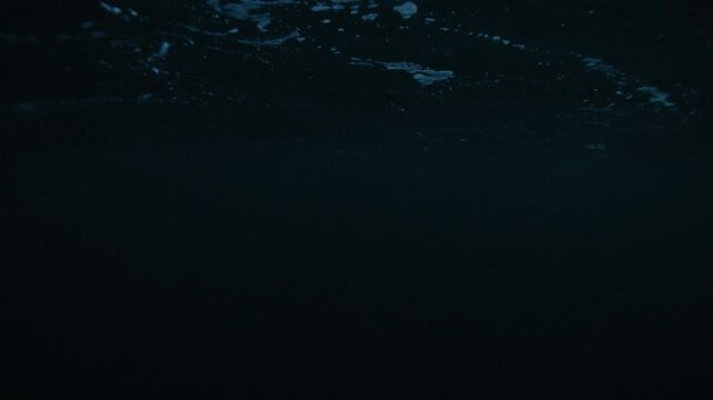 Deep underwater Arctic Ocean with faint light patterns shimmering across dark water
