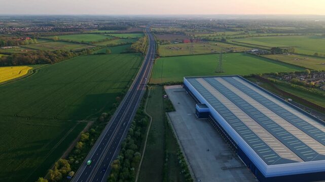 Aerial view of a huge industrial distribution warehouse complex at golden hour sunset near Doncaster, UK.