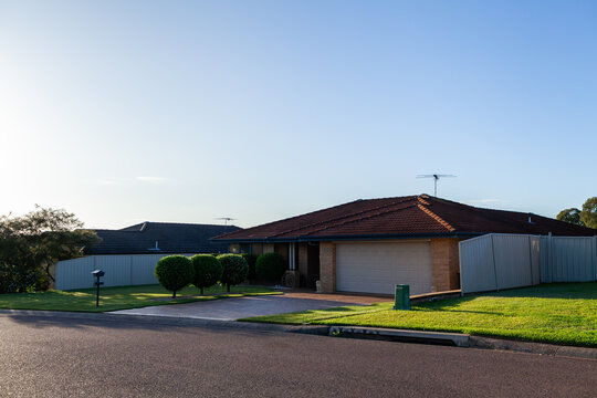 Neat home with hedged trees along driveway in suburbia