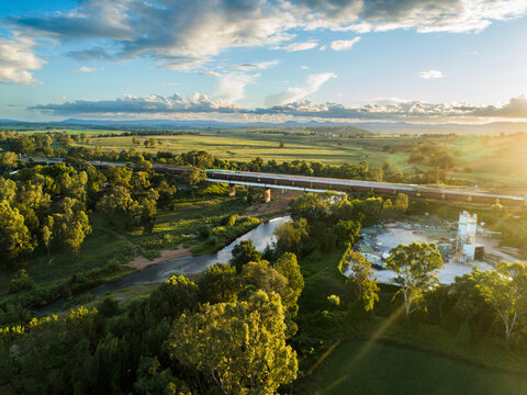 Cement plant and railway line with coal train at sunset crossing bridge over hunter river