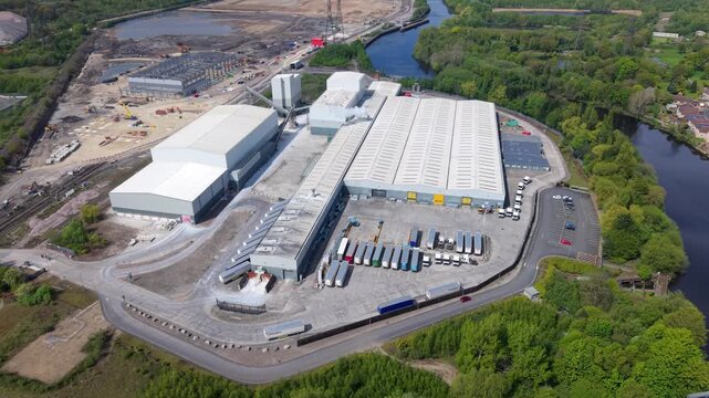 High angle aerial drone view of a large industrial factory and logistics distribution center with HGVs in loading bays in the UK