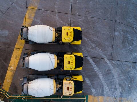 Three cement mixers parked at concrete plant facility