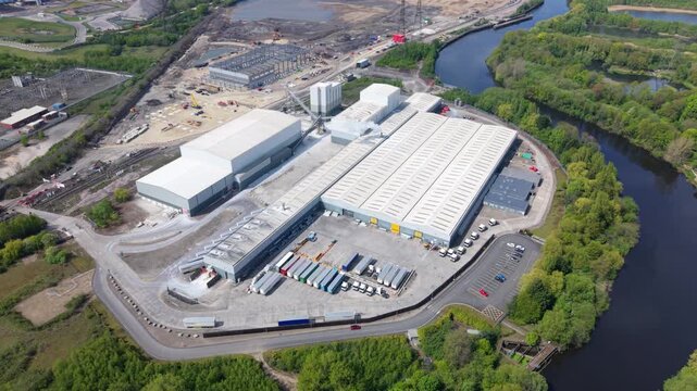 High angle aerial drone view of a large industrial factory and logistics distribution center with HGVs in loading bays in the UK