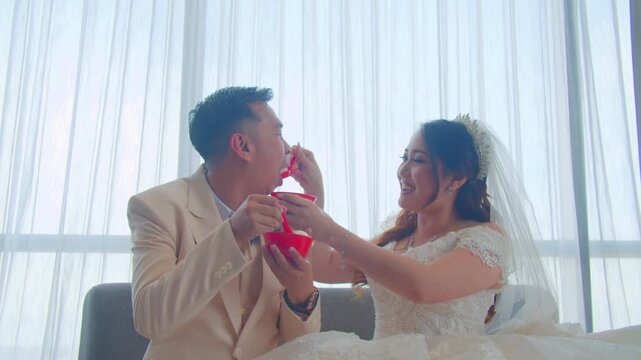 A joyful bride and groom sharing a romantic kiss, enjoying their wedding cake, and posing happily on a beautifully decorated stage during their wedding celebration.