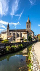 Obraz premium Scenic shot of a cathedral by a river, on a sunny day with blue sky