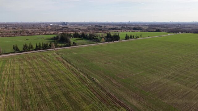 Drone shot flying forward over green agricultural fields and a highway near the former Toronto Markham Airport, with the city skyline on the horizon