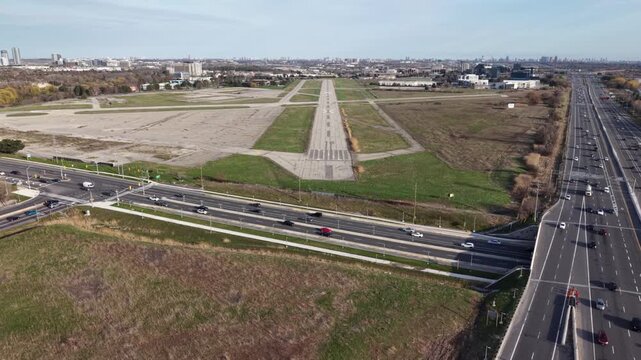Cinematic drone shot flying forward along the length of decommissioned runway 15/33 at Buttonville Municipal Airport, revealing closure markings and neighboring Highway 404 in Markham