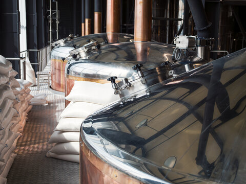 Craft brewhouse kettles with malt bags, copper and steel brewing equipment, beer production process, beverage industry.