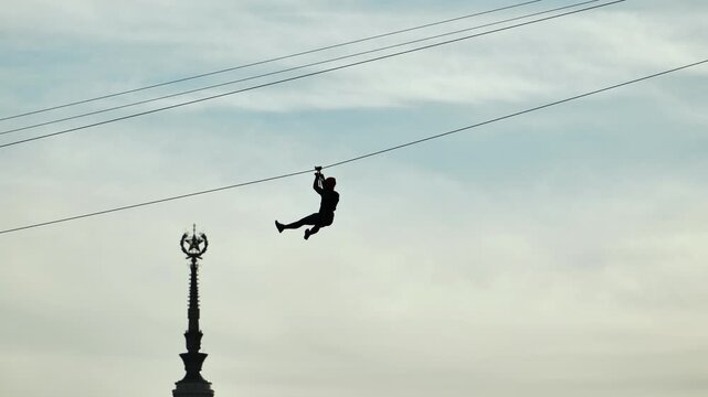 Person ziplining across the sky with a Moscow landmark in the background