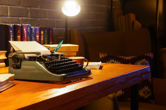 Vintage typewriter with glowing lamp on author's desk in dark office