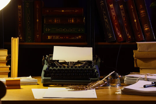 Author's workplace with vintage typewriter and books in dark office